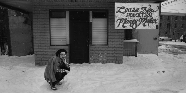 Wintfred Huskey crouching in front of a shop