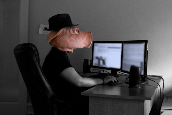 man with pig's head sitting at desk in front of computer 