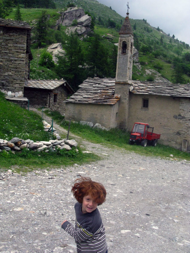 Near Torino, pictured is the author's son at age 6. A young boy in front of an old stone building at the base of a green hill