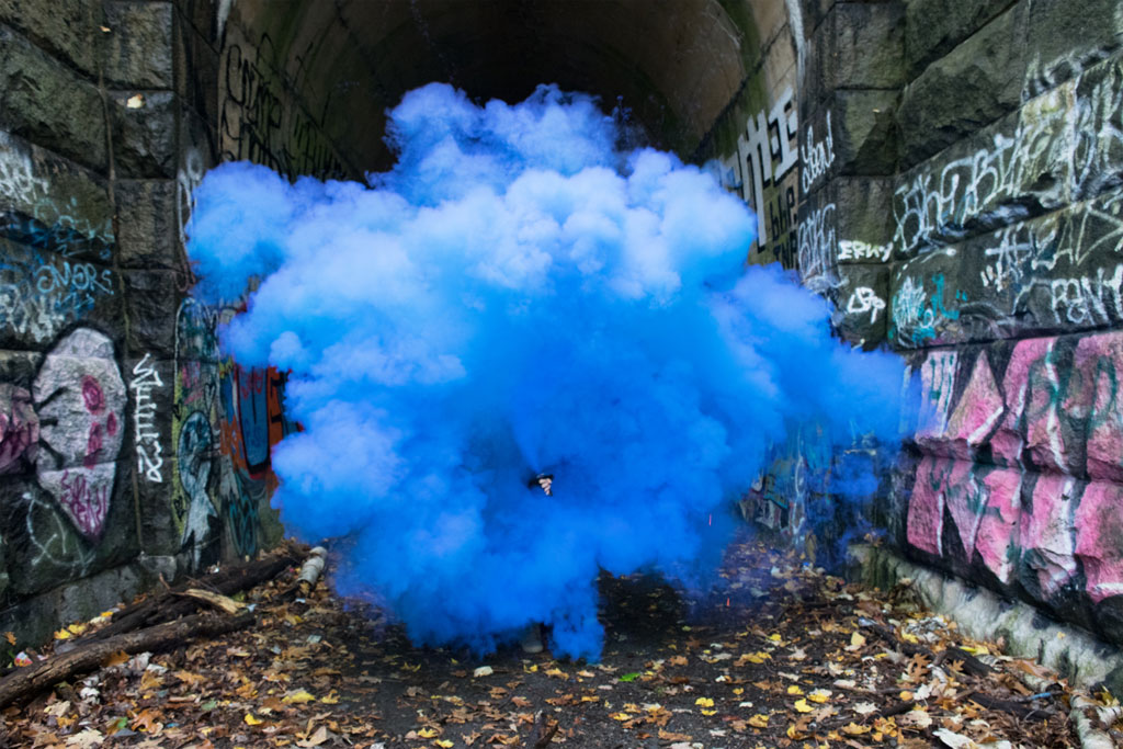 becoming-an-outlaw, bright blue smoke cloud in graffitied alleyway