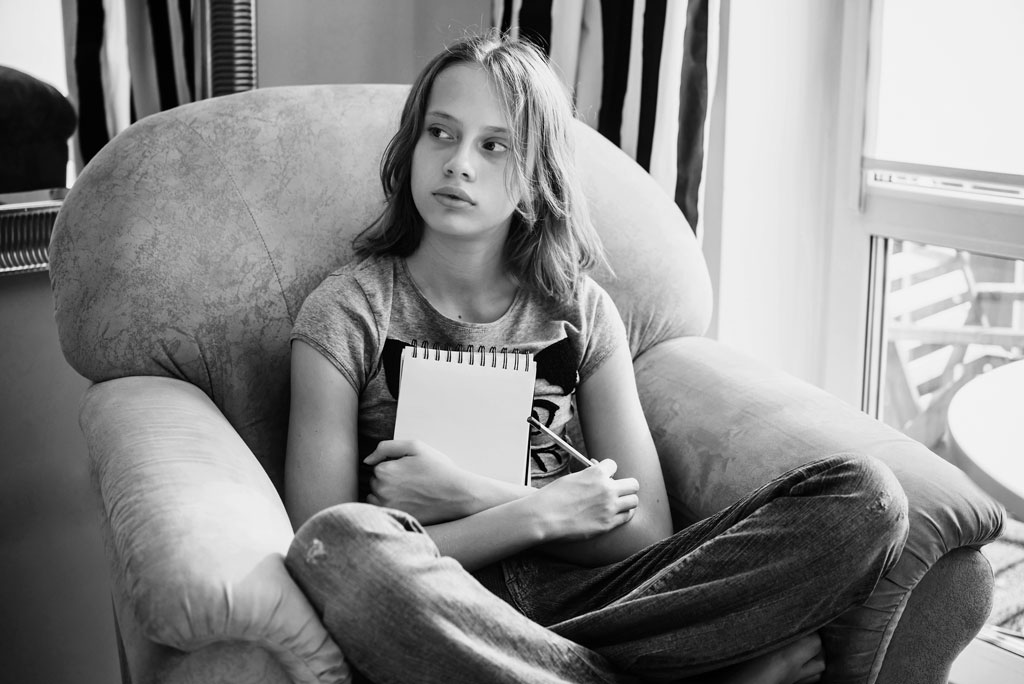intent-to-withhold, black and white photo of girl holding notebook and pencil sitting on armchair