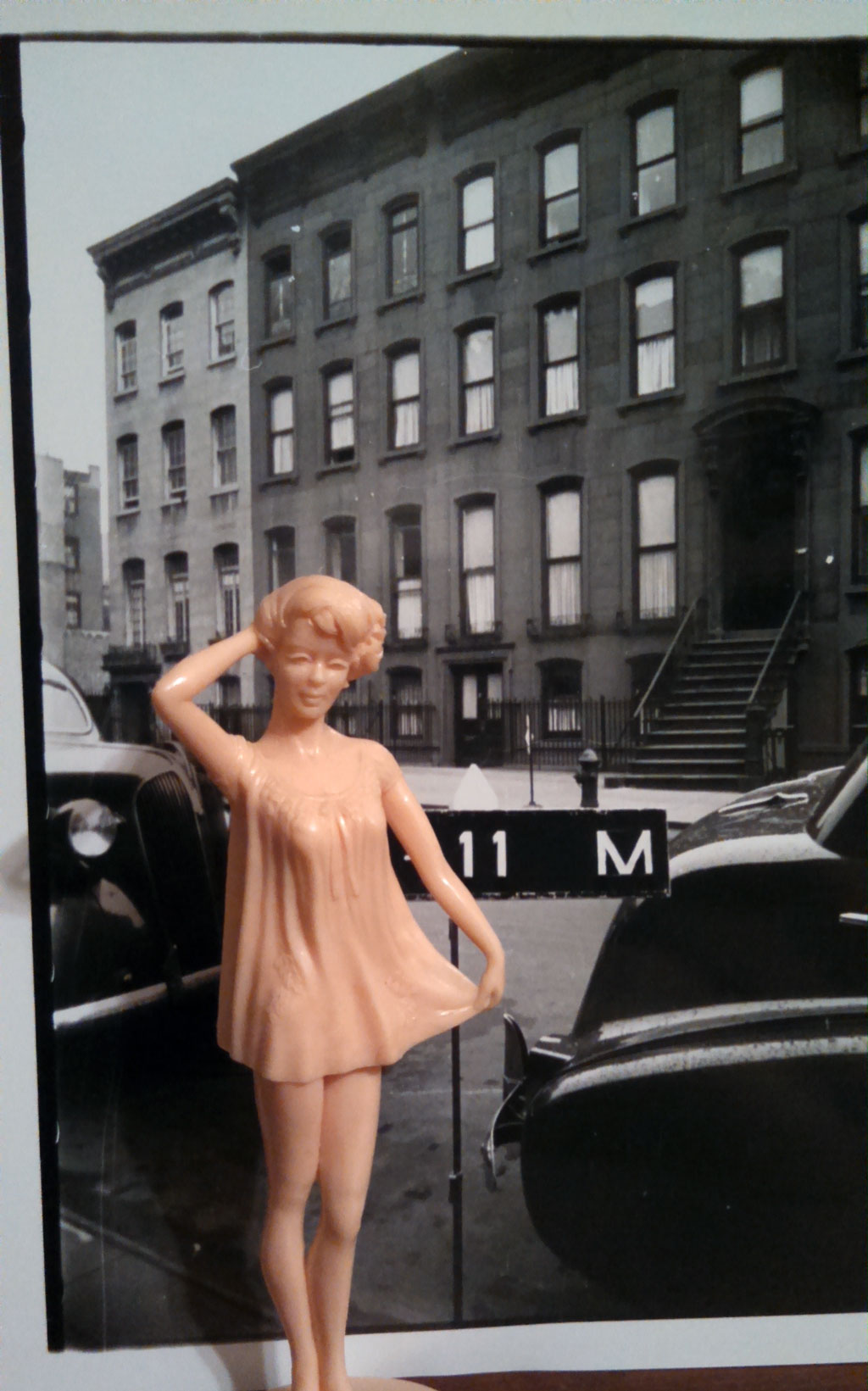 doll in front of black and white photo of residential building