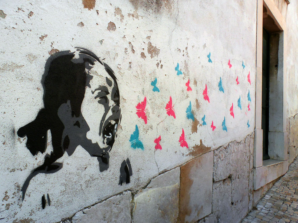 Graffiti of man with mouth open and pink and blue butterflies flying out