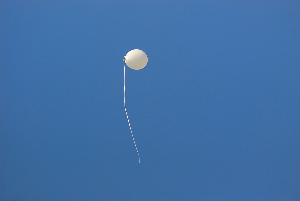 White balloon floating against a bright blue sky