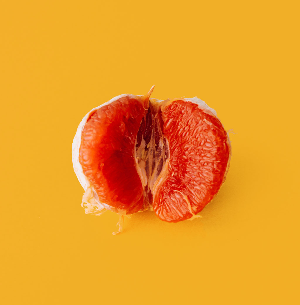Half of a grapefruit against a yellow background