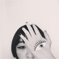 Gloria Yuen with an eye painted on one of her hands that covers her eye 