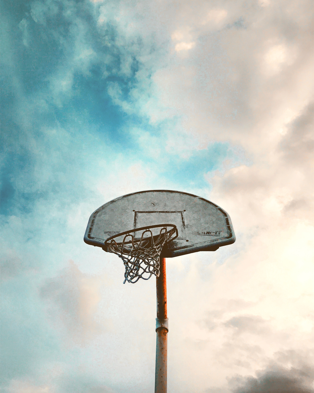 Old basketball goal with blue cloudy sky