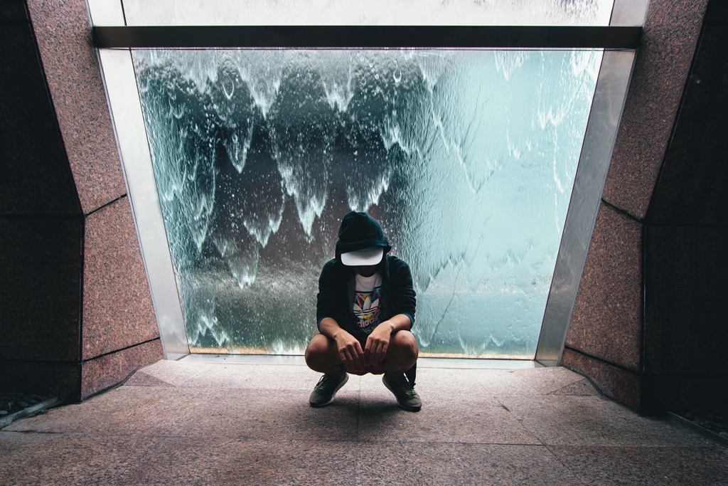 Man squatting in front of icy window