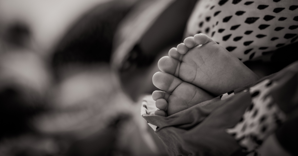 Black-and-white image of infant's feet cradled in fabric