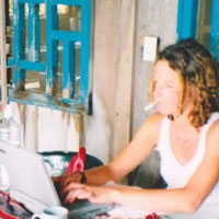 Photo of Jennifer Todhunter typing on her computer and smoking a cigarette