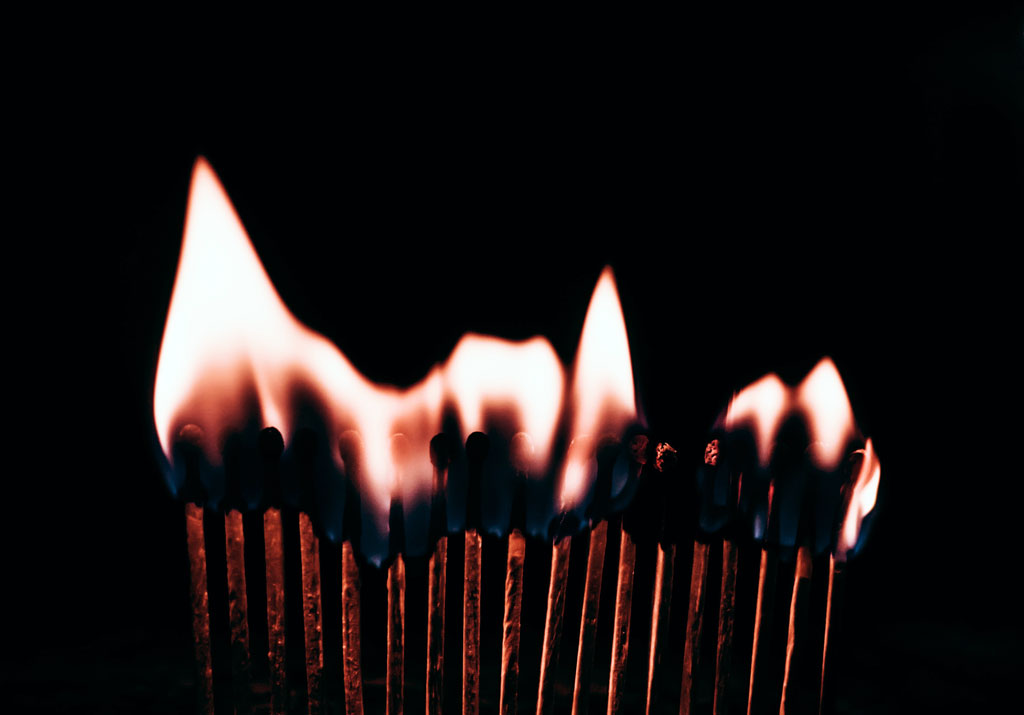 row of matches on fire against black background