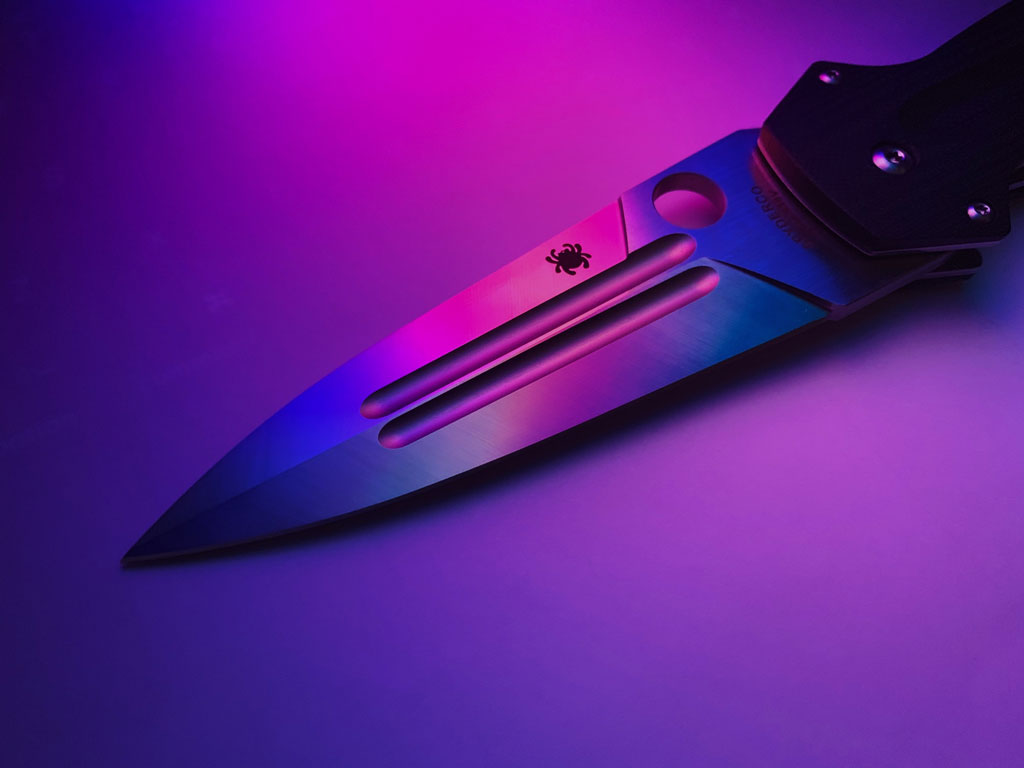 A folding knife against a pink neon background