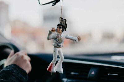 a plastic elvis figurine hanging from a car's rear view mirror