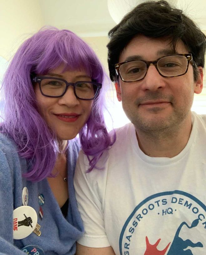 woman in long purple wig; man in shaggy black wig; political attire