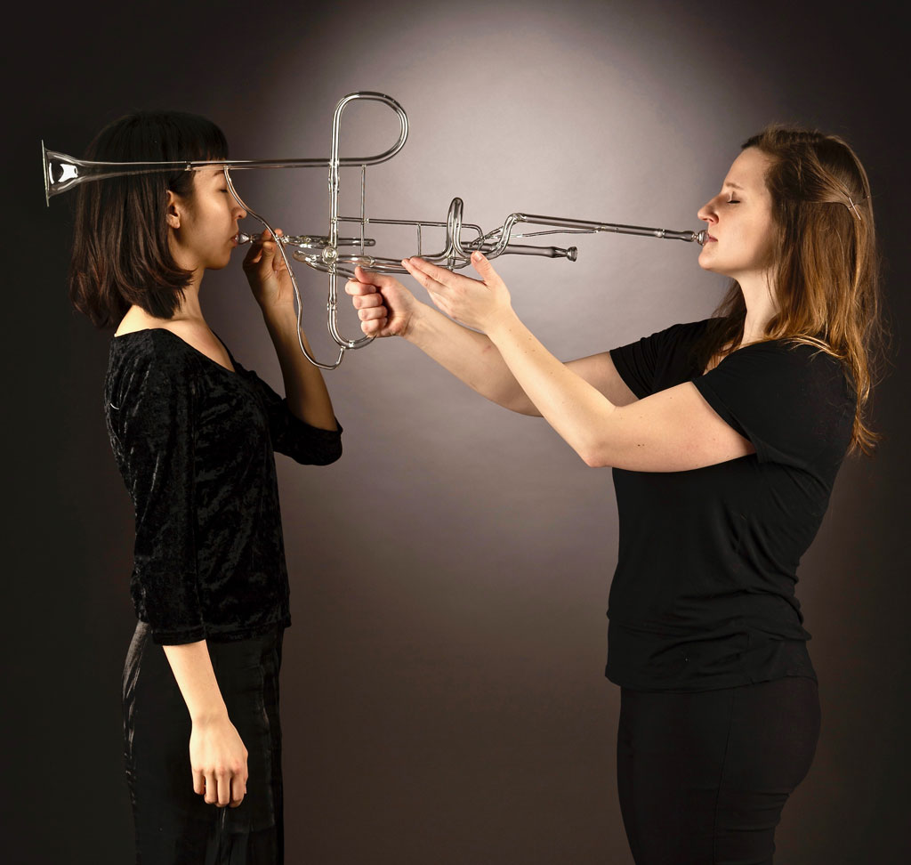 two women playing a glass trumpet