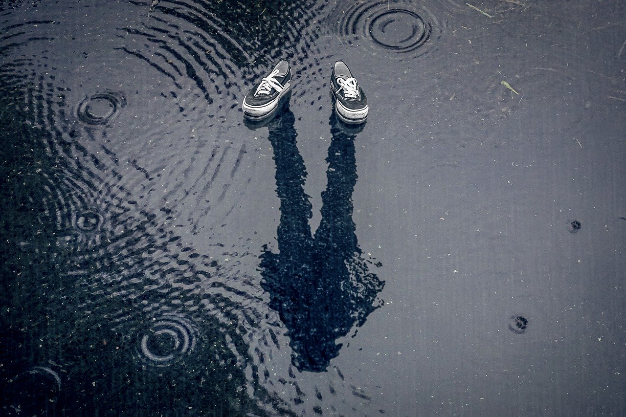 A pair of sneakers with a mysterious shadow, in the rain