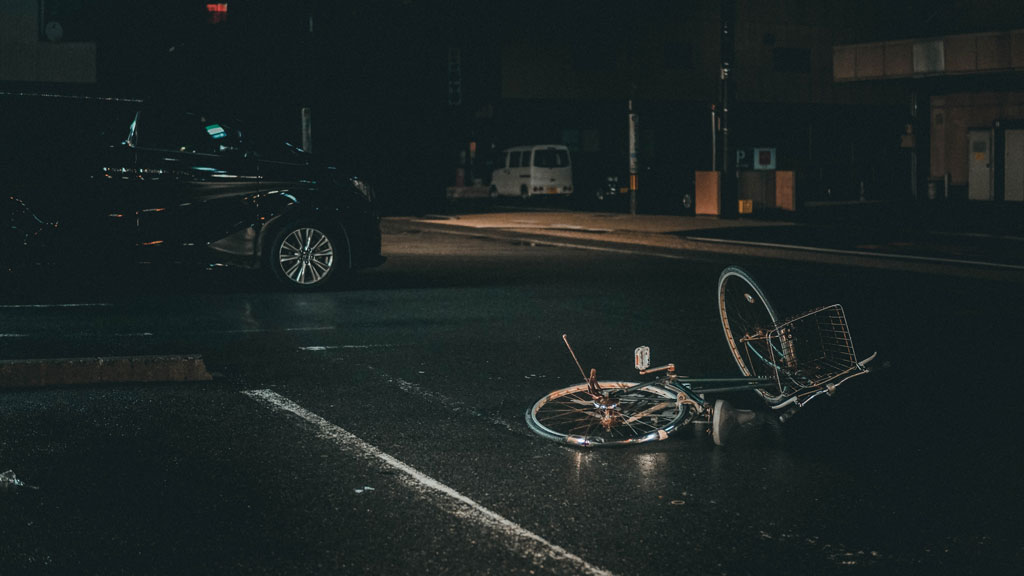 a bicycle lying in the roadway at night in the rain