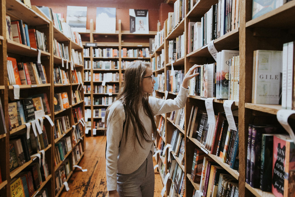 A woman browsing the fiction section of a bookstore