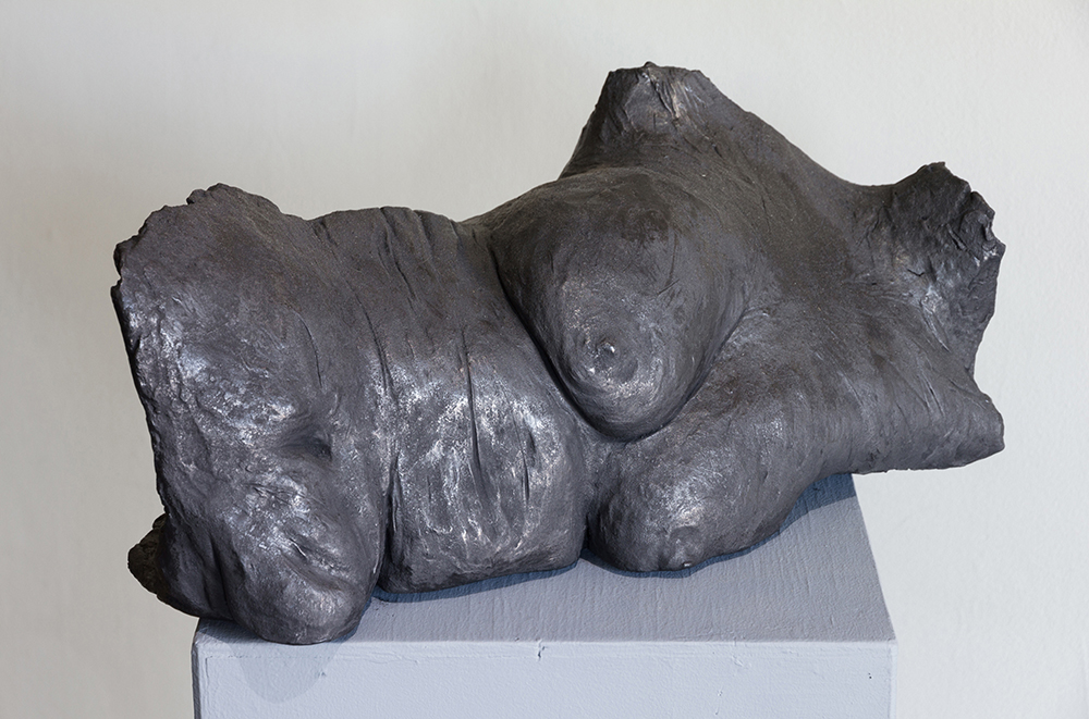 Sculpture of woman's chest and torso laying horizontally